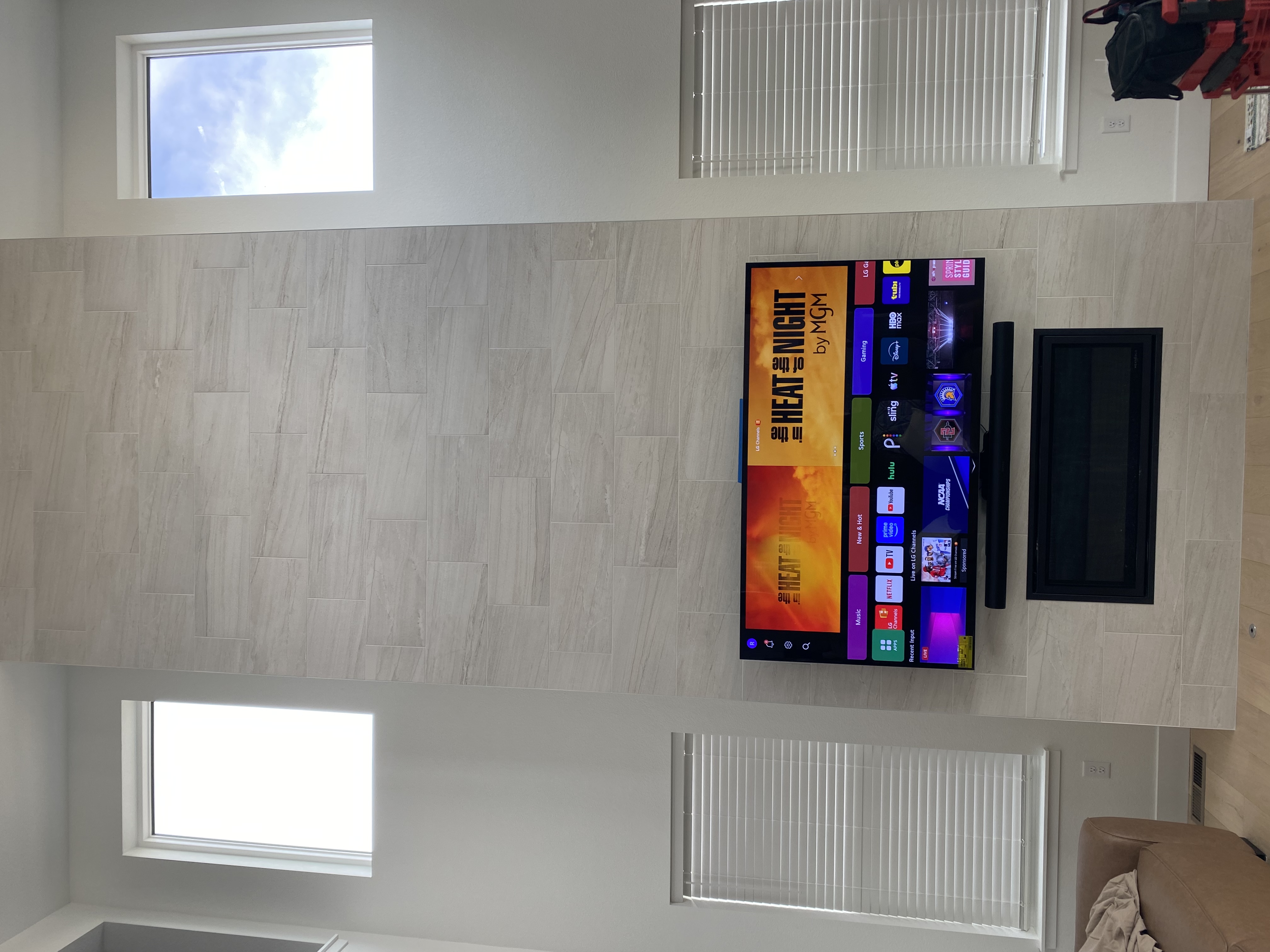 TV mounted on tile wall above fireplace with soundbar